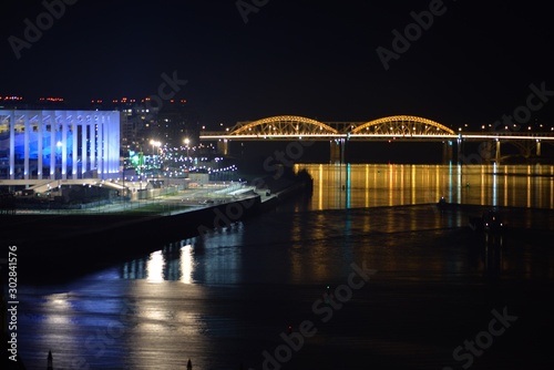 Night view of the Nizhny Novgorod stadium and the bridge across the Volga, reflected in the water