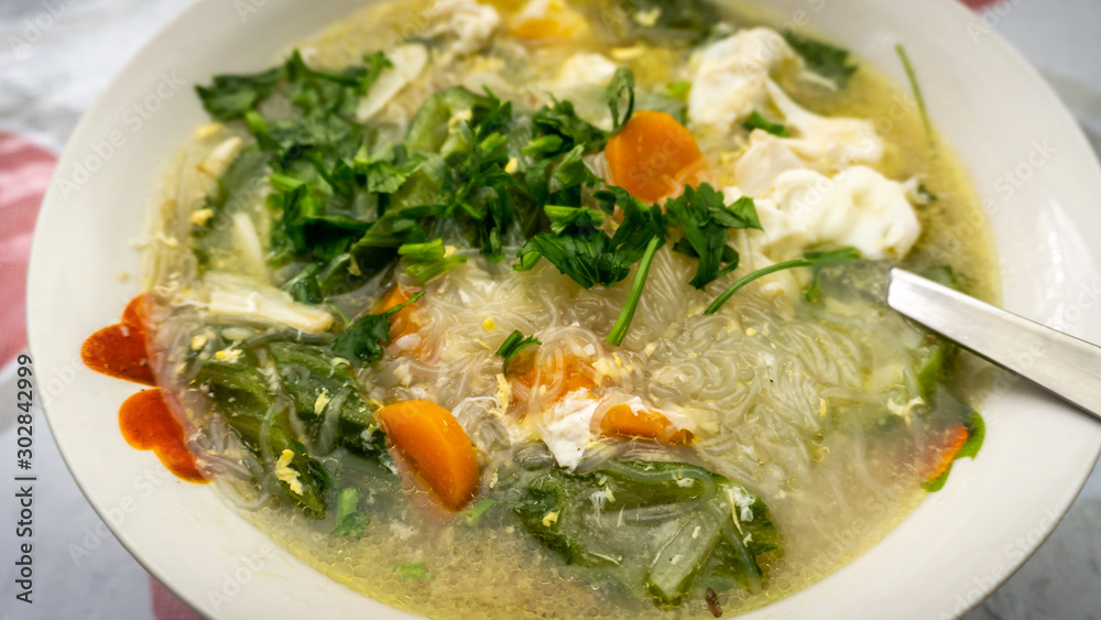 The close up view of the mixed vegetables soup with soo hoon noodles in a bowl. The close up view of the mixed vegetables soup with soo hoon noodles in a bowl.