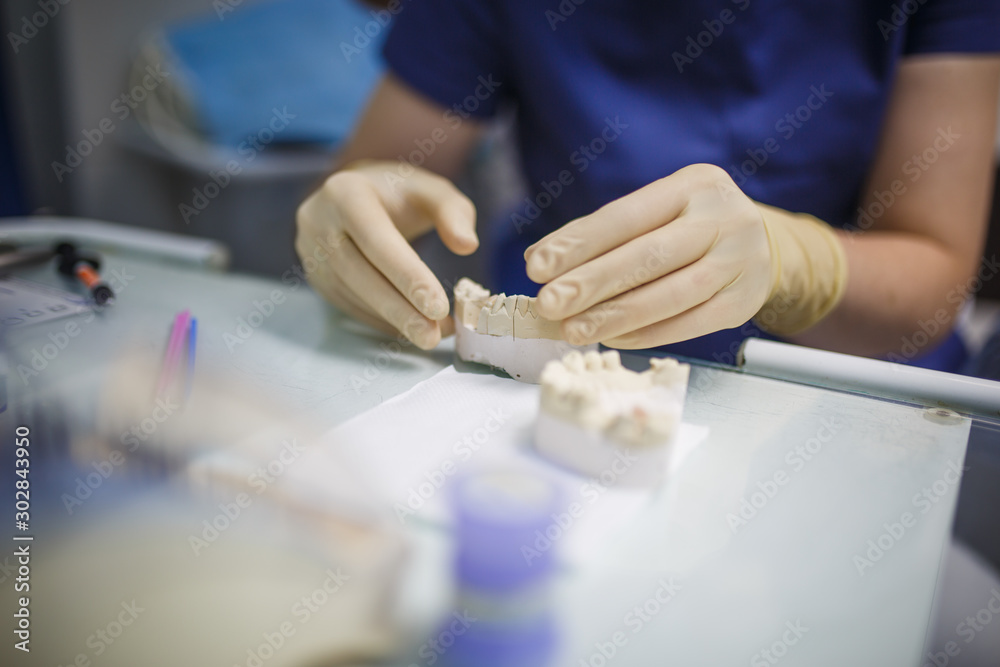 Dentist's hands in rubber gloves in the process of treatment and prosthetics. Doctor's hand with dental instrument.