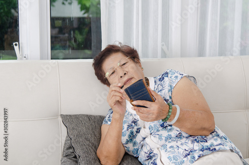 Asian senior woman using smartphone on sofa. Lifestyle concept.