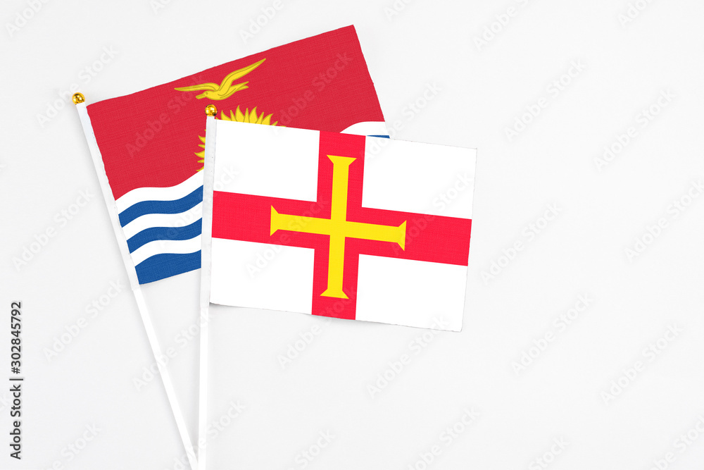 Guernsey and Kiribati stick flags on white background. High quality fabric, miniature national flag. Peaceful global concept.White floor for copy space.