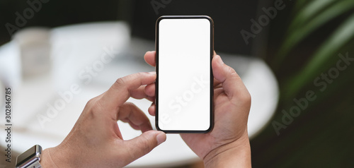 Cropped shot of man holding smartphone with outdoor workplace background