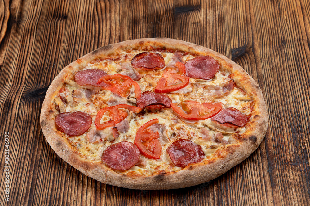 Classic salami pizza with melted cheese on wooden rustic table