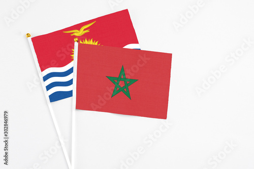 Morocco and Kiribati stick flags on white background. High quality fabric, miniature national flag. Peaceful global concept.White floor for copy space.
