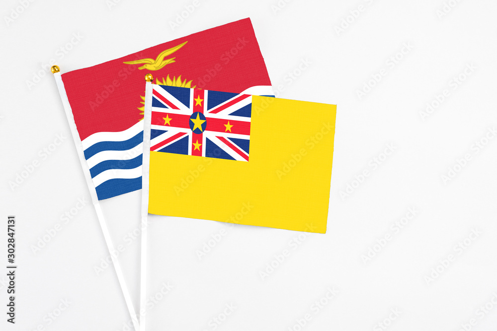 Niue and Kiribati stick flags on white background. High quality fabric, miniature national flag. Peaceful global concept.White floor for copy space. Niue and Kiribati stick flags on white background. High quality fabric, miniature national flag. Peaceful global concept.White floor for copy space.