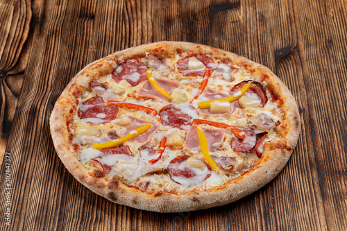 Meat pizza with ham and fresh bell pepper on wooden table
