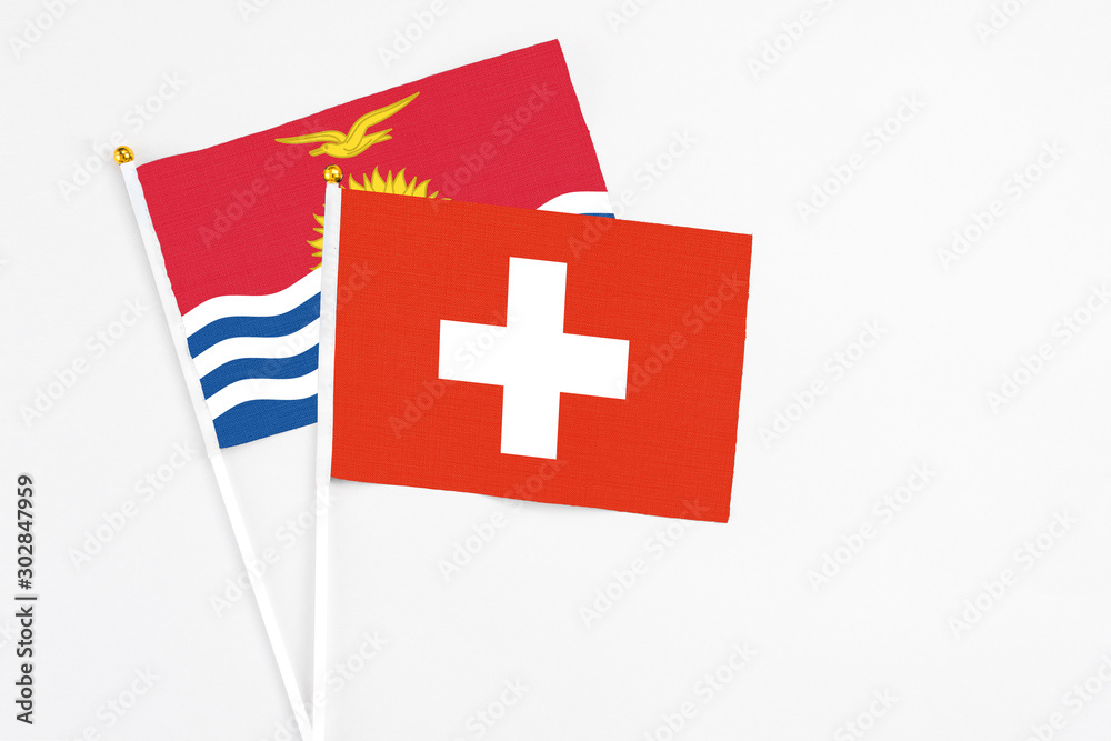 Switzerland and Kiribati stick flags on white background. High quality fabric, miniature national flag. Peaceful global concept.White floor for copy space.