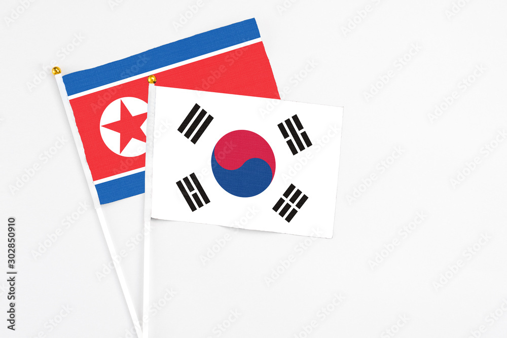 South Korea and North Korea stick flags on white background. High quality fabric, miniature national flag. Peaceful global concept.White floor for copy space.