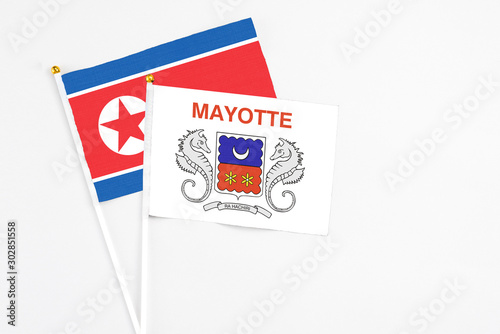 Mayotte and North Korea stick flags on white background. High quality fabric, miniature national flag. Peaceful global concept.White floor for copy space.