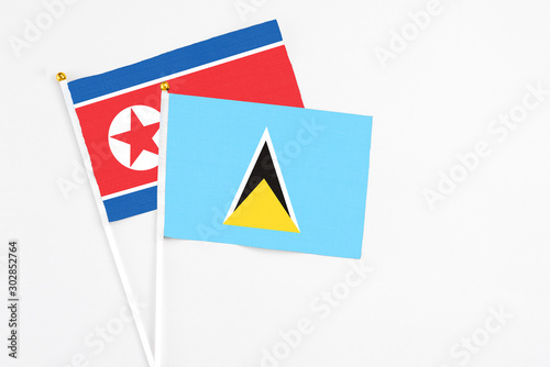Free Download Saint Lucia and North Korea stick flags on white background. High quality fabric, miniature national flag. Peaceful global concept.White floor for copy space. - GFXLoad