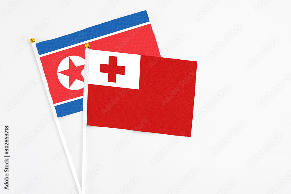 Tonga and North Korea stick flags on white background. High quality fabric, miniature national flag. Peaceful global concept.White floor for copy space.