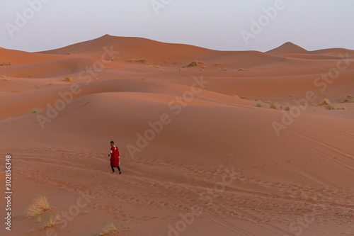 Person walking through the dunes of the Sahara desert. Morocco