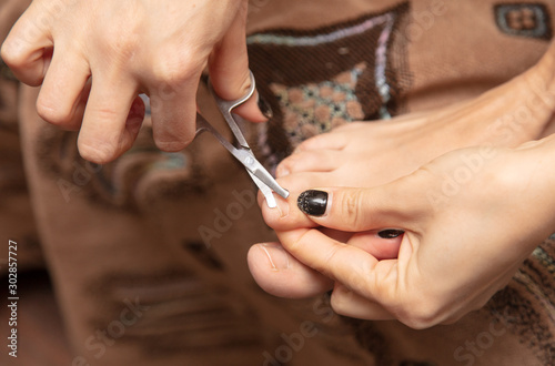 Girl cuts toenails with scissors