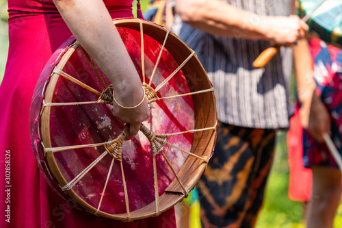 Sacred drum during spiritual singing. A close-up view and side view of women hand holding her sacred native drum, with a lot of people in the background photo