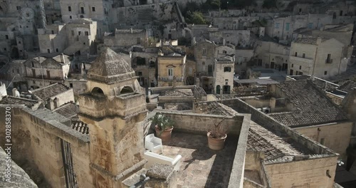 Roofs of houses in the Sassi of Matera transformed into hotels. Panoramic terrace with sofa and chair in white plastic.