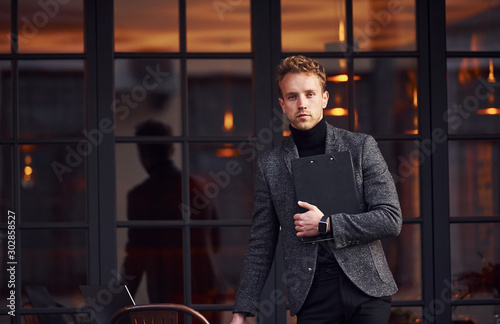 Man in elegant formal wear outside against modern building