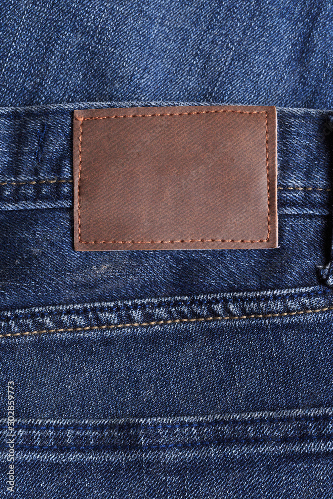 Highly detailed closeup of blank grungy leather label on worn blue denim with orange seams, good for background - Image Highly detailed closeup of blank grungy leather label on worn blue denim with orange seams, good for background - Image