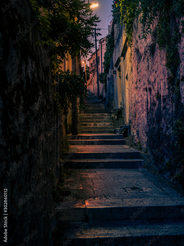 Vertical photo of a narrow alley at night in the city of Dubrovnik