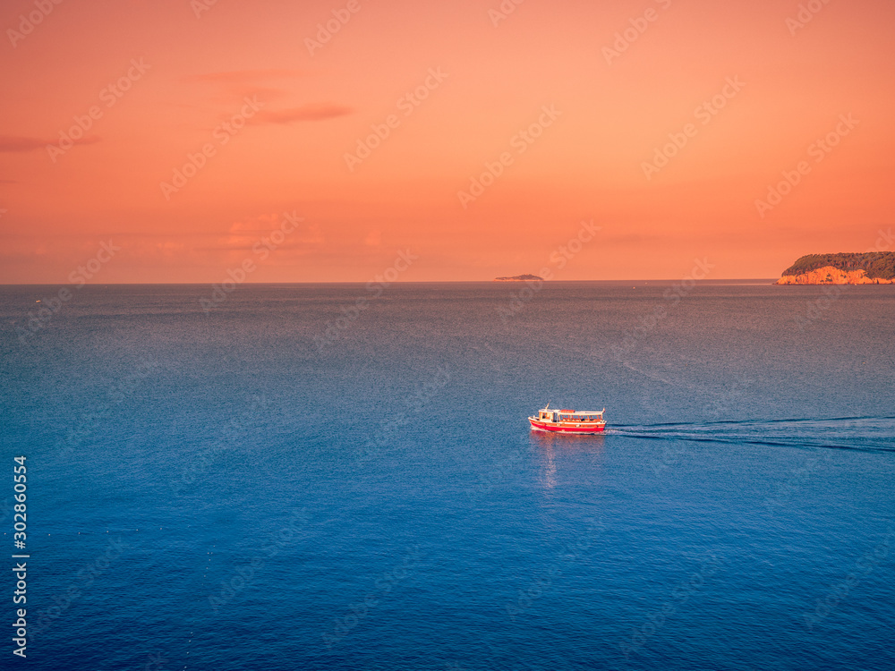 Sunset on the sea with a small boat sailing