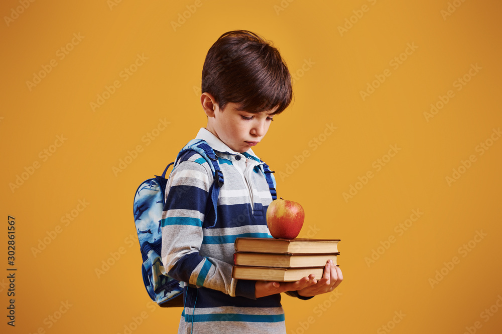 Portrait of young smart schooler in the studio against yellow background Portrait of young smart schooler in the studio against yellow background