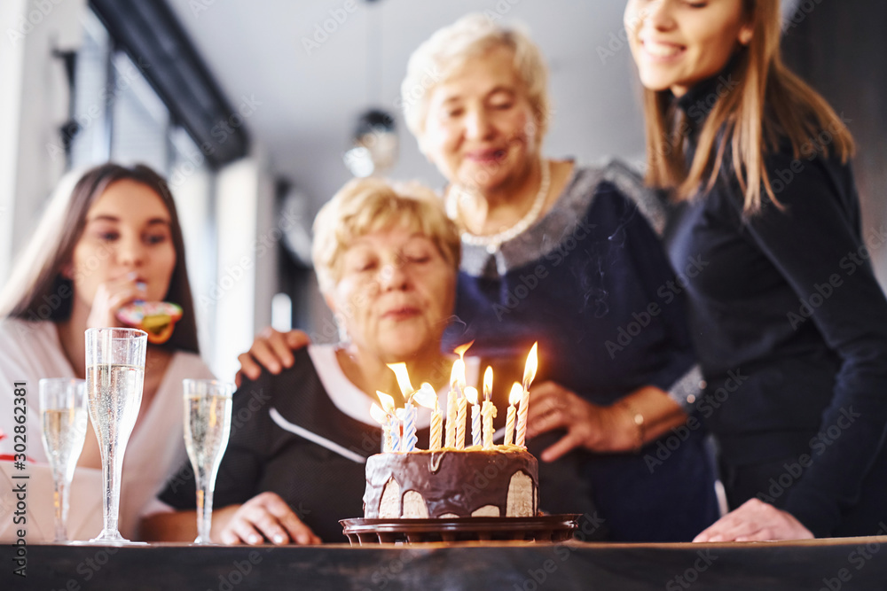 Blowing the candles. Senior woman with family and friends celebrating a birthday indoors Blowing the candles. Senior woman with family and friends celebrating a birthday indoors