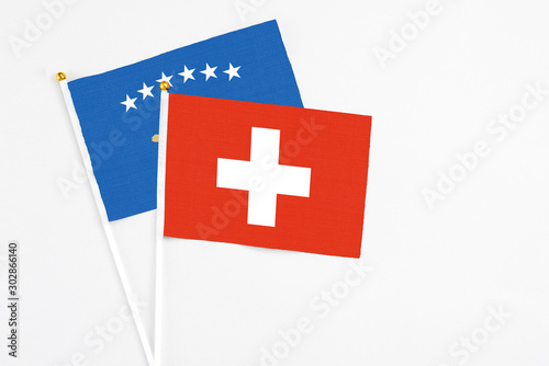 Switzerland and Kosovo stick flags on white background. High quality fabric, miniature national flag. Peaceful global concept.White floor for copy space. photo