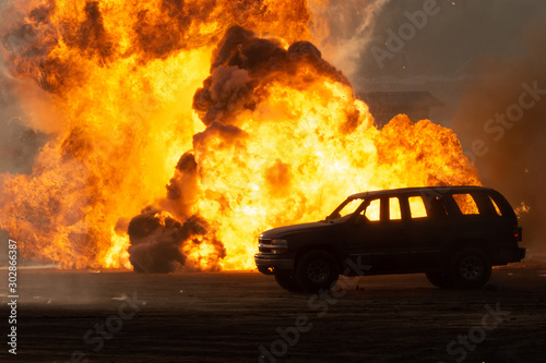 Close up of a Military strike or bomb in war on an SUV with tanks causing fire balls and explosion in the town in chaos. Military war concept. Strength, power, force, fire, explosion. photo