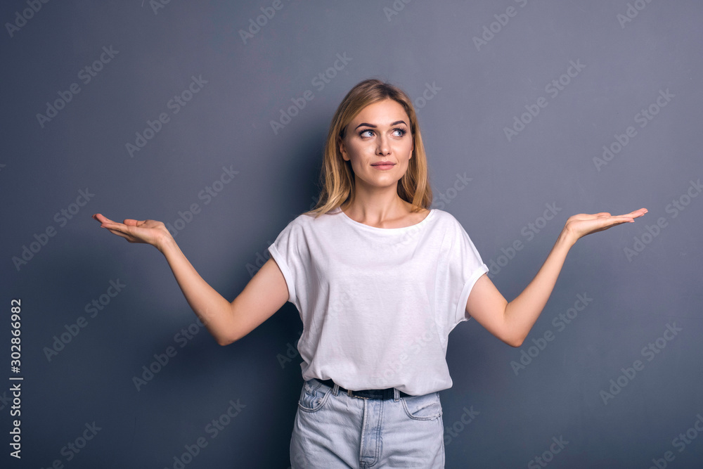 Caucasian woman in neutral casual outfit standing on a neutral grey background. Portrait with emotions: happiness, amazement, joy and satisfaction Caucasian woman in neutral casual outfit standing on a neutral grey background. Portrait with emotions: happiness, amazement, joy and satisfaction