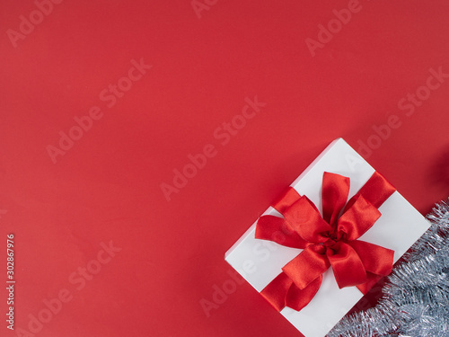 White gift box with red ribbon on red background