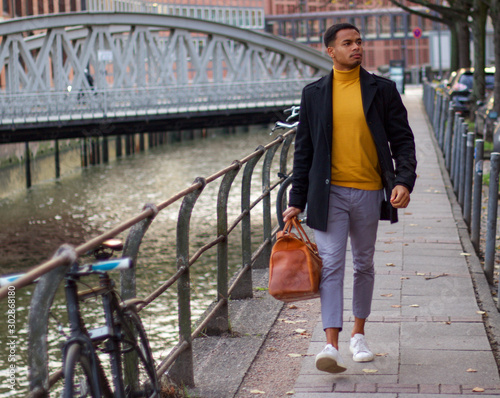 junger schwarzer Mann geht mit seiner Reisetasche durch Hamburg © Esquire