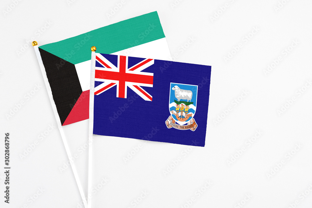 Fototapeta premium Falkland Islands and Kuwait stick flags on white background. High quality fabric, miniature national flag. Peaceful global concept.White floor for copy space.
