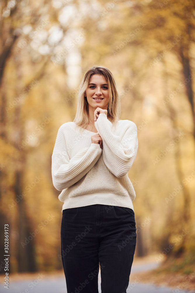 In warm clothes. Portrait of young brunette that is in autumn forest at daytime In warm clothes. Portrait of young brunette that is in autumn forest at daytime