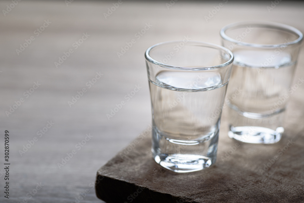 Vodka in a shot glass on a brown wooden background prepared for a party Vodka in a shot glass on a brown wooden background prepared for a party