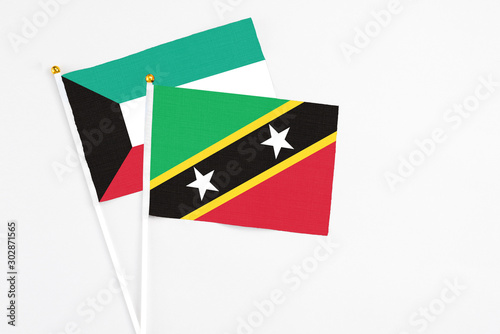 Free Download Saint Kitts And Nevis and Kuwait stick flags on white background. High quality fabric, miniature national flag. Peaceful global concept.White floor for copy space. - GFXLoad
