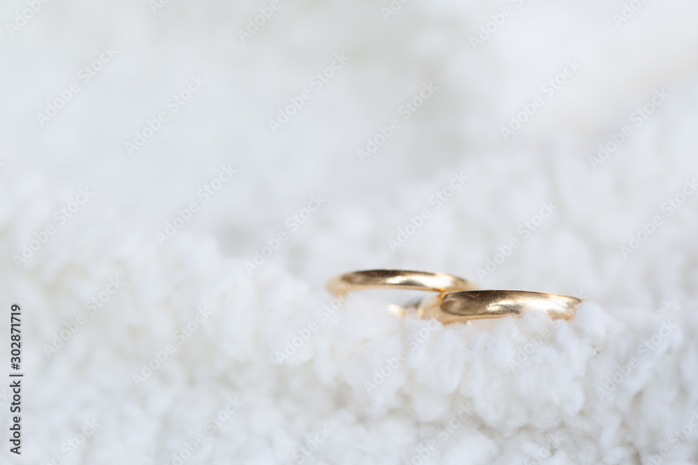 Fototapeta premium Golden wedding rings on white soft wool