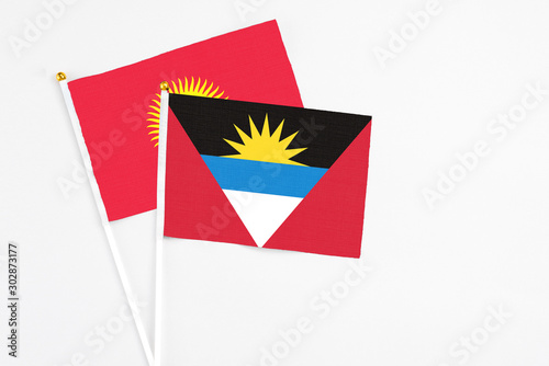 Antigua and Barbuda and Kyrgyzstan stick flags on white background. High quality fabric, miniature national flag. Peaceful global concept.White floor for copy space.