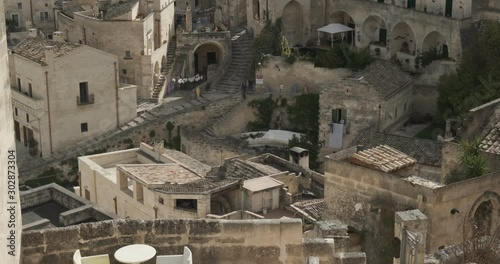 Roofs of houses in the Sassi of Matera transformed into hotels. Panoramic terrace with sofa and chair in white plastic.
