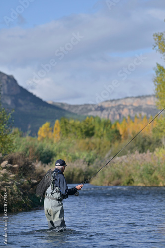fly fisherman in autumn and fast river