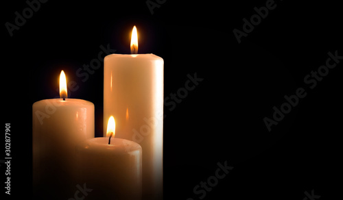 Three burning candles isolated black front view photo