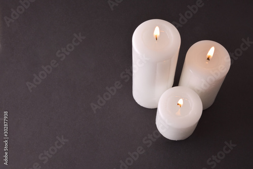 Three burning candles on gray degrading background top view