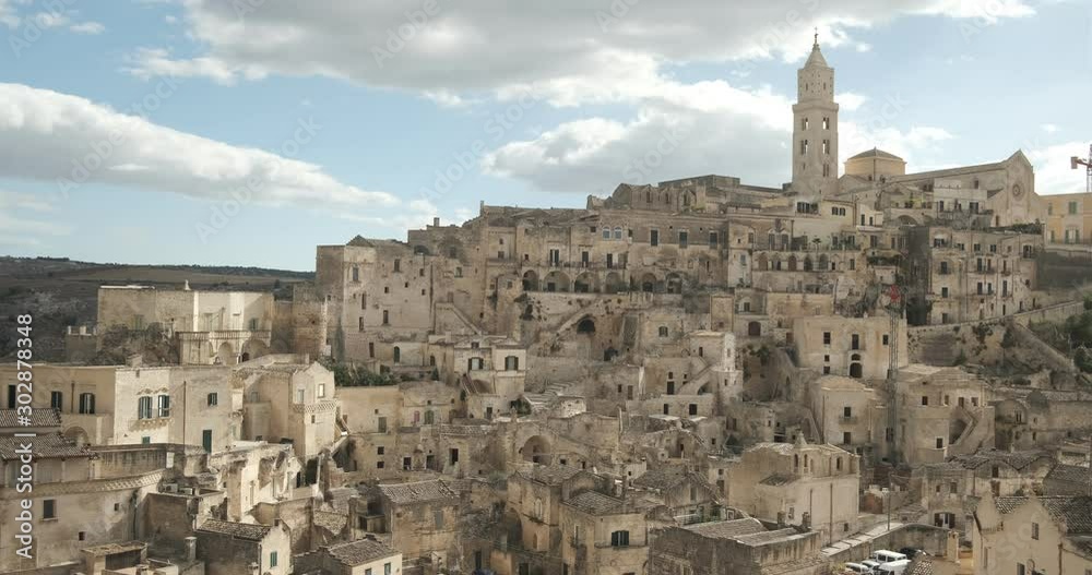Panorama of the Sassi of Matera with houses in tuff stone. Church with bell tower and stone arch at dawn with sky and clouds. Panorama of the Sassi of Matera with houses in tuff stone. Church with bell tower and stone arch at dawn with sky and clouds.