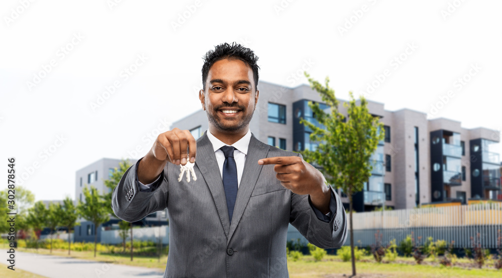 real estate business and people concept - indian man realtor with keys over living houses on city street background real estate business and people concept - indian man realtor with keys over living houses on city street background