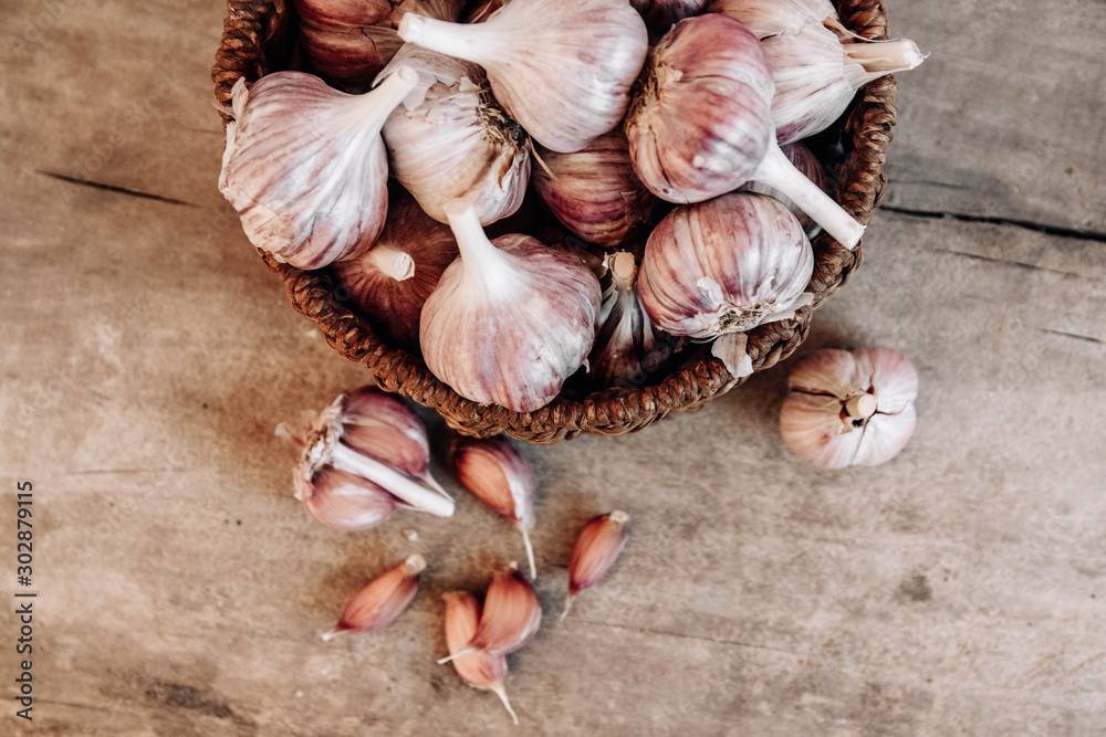 Garlic in a wicker basket on a wooden table background. Top view. Copy, empty space for text