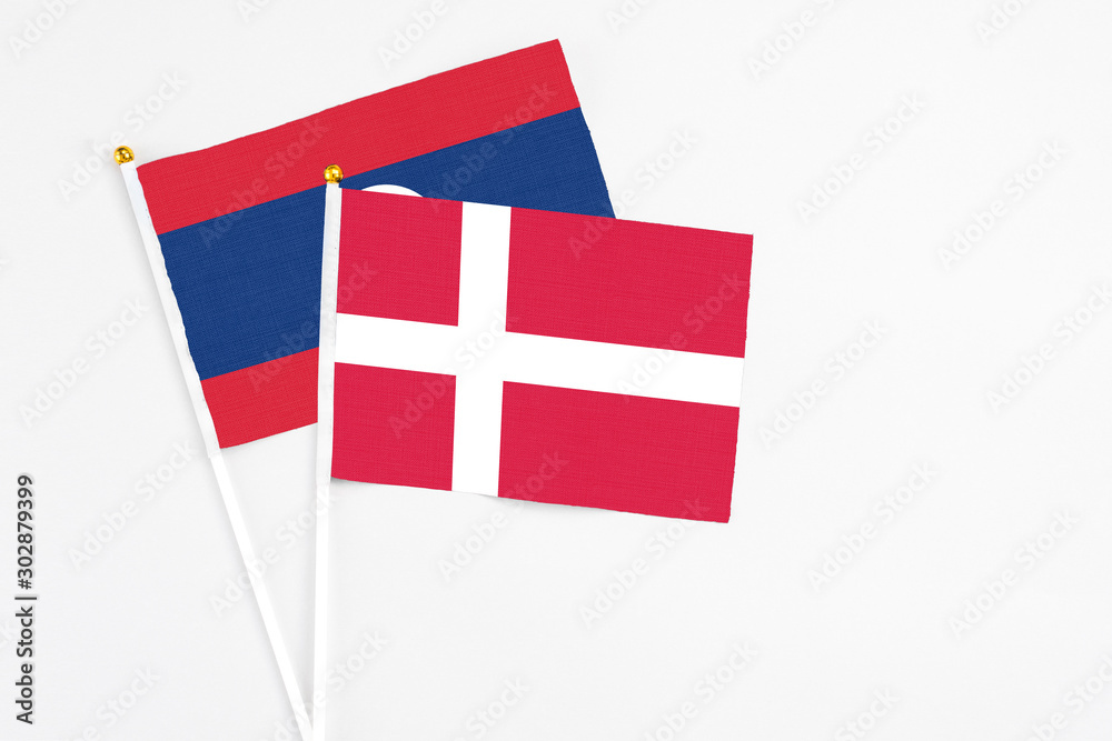 Denmark and Laos stick flags on white background. High quality fabric, miniature national flag. Peaceful global concept.White floor for copy space.