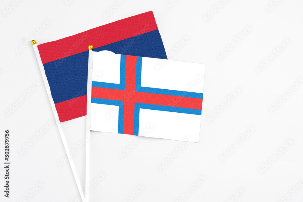 Faroe Islands and Laos stick flags on white background. High quality fabric, miniature national flag. Peaceful global concept.White floor for copy space.