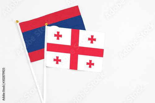 Georgia and Laos stick flags on white background. High quality fabric, miniature national flag. Peaceful global concept.White floor for copy space.