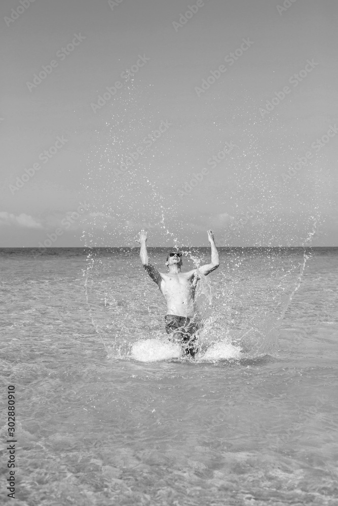 Obraz premium young muscular man posing and splashing around in the sea