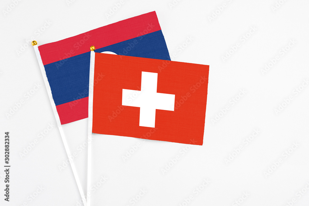 Switzerland and Laos stick flags on white background. High quality fabric, miniature national flag. Peaceful global concept.White floor for copy space.