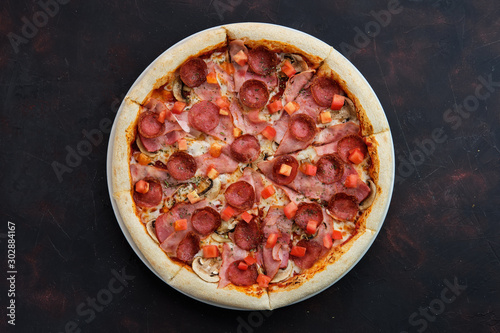 Top view of pizza with ham, bacon, sausage, tomato and champignon