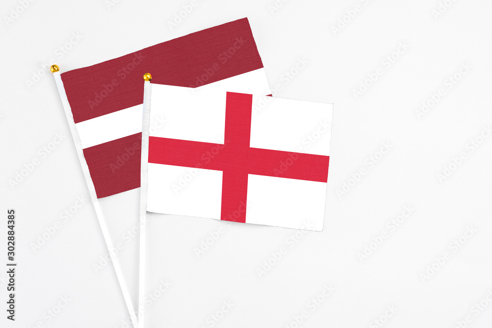 England and Latvia stick flags on white background. High quality fabric, miniature national flag. Peaceful global concept.White floor for copy space.